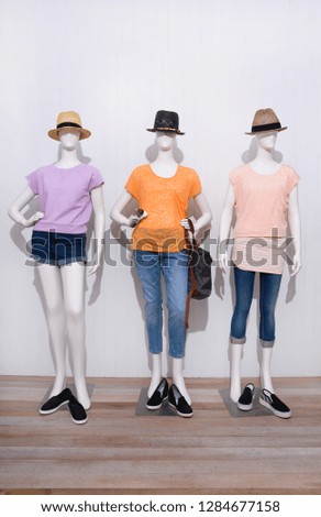 Three full mannequin in female shirt with blue , shorts jeans shoes ,hat,sunglasses -wooden background  
