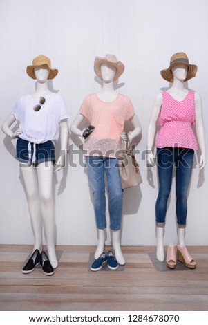 Three full mannequin in female shirt with blue , shorts jeans shoes ,hat,sunglasses -wooden background
