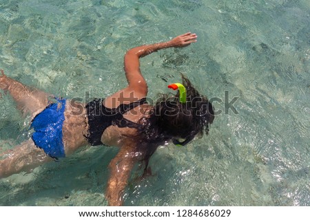 Aerial view of young woman in bright bikini is swimming in the transparent, blue sea. Top view of slim woman floating on the water of Andaman sea. Khai Nok island, Phuket, Thailand.