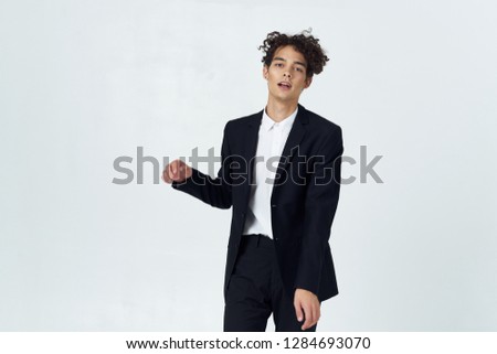 A guy in a classic suit on a gray background gesticulating with his hands                         