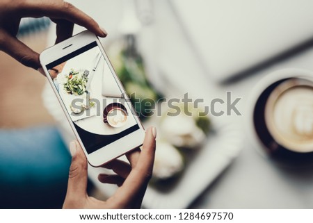 Cropped photo of ladies hands holding cellular and making photo of her organic nutrition lunch on blurred bakground