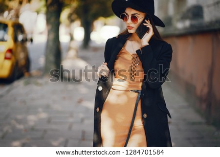 styligh woman uses her cell phone as she walks through the city on a sunny warm day