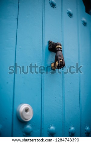 Beautiful old wooden door painted blue with a knob in shape of a hand