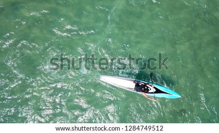 Aerial drone top view photo of sport SUP or Stand Up Paddle practising man downwind in tropical bay with open ocean sea