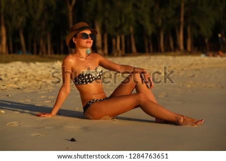 Young girl posing on the beach sitting on the sand