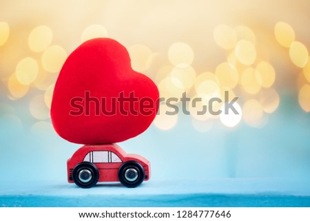Miniature red car carrying a red heart on shine bokeh background