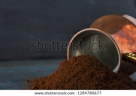 Closeup of ground coffee against coffee pot and dark wall