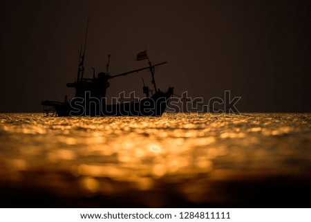 The fisherman boat silhouette on the sea with sunset sky