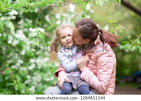 Portrait of mother with daughter in summer park. Woman with child hugging