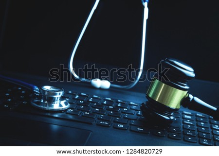 Gavel with medical stethoscope on laptop keyboard.