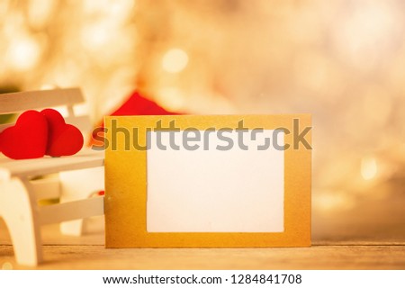Concept of Valentine, anniversary, wedding greeting with a picture frame, heart shapes on a white wooden bench, bokeh background, close up