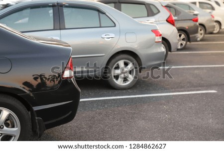 Closeup of back or rear side of black car with  other cars parking in parking area with natural background in the evening of sunny day. The mean of simply transportation in modern world.