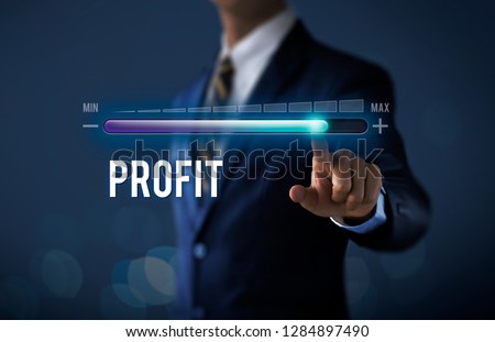 Profit growth, increase profit, raise profit or business growth concept. Businessman is pulling up progress bar with the word PROFIT on dark tone background. Royalty-Free Stock Photo #1284897490