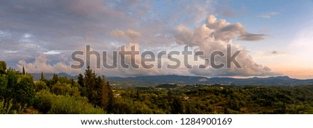 Beautiful panoramic view of Corfu island covered with forest and colorful clouds in sunset sky, Greece