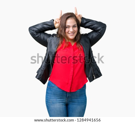 Beautiful plus size young woman wearing a fashion leather jacket over isolated background Posing funny and crazy with fingers on head as bunny ears, smiling cheerful