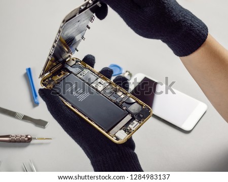 Technician or engineer opening broken smartphone for repair or replace new part on desk Royalty-Free Stock Photo #1284983137