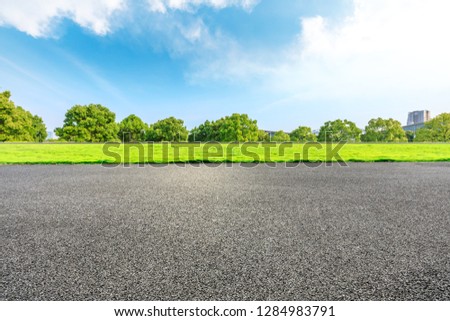 Urban asphalt road and green trees under blue sky