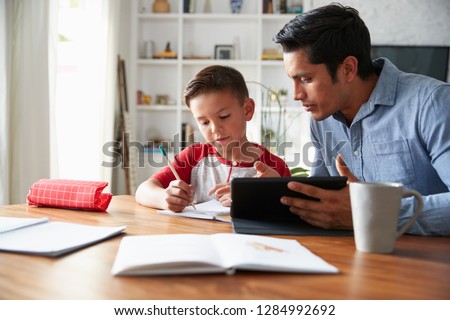 Hispanic pre-teen boy sitting at dining table working with his home school tutor Royalty-Free Stock Photo #1284992692