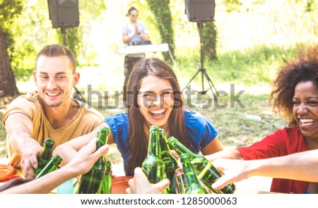 Multiracial millenial friend having fun at barbecue garden party with music - Friendship concept with young happy people toasting beer bottle at summer hangout - Guys and girls on warm sunshine filter