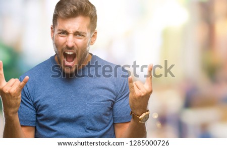 Young handsome man over isolated background shouting with crazy expression doing rock symbol with hands up. Music star. Heavy concept.