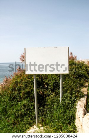 Blank advertising billboard display and table, sea in background. Advertising agencies. Billboard with copy space for text message or content, outdoor advertising mock up, public information board.