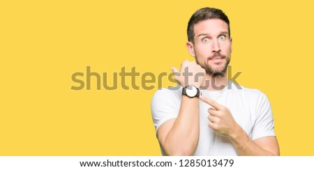 Handsome man wearing casual white t-shirt In hurry pointing to watch time, impatience, upset and angry for deadline delay Royalty-Free Stock Photo #1285013479