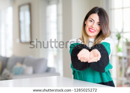 Young beautiful woman wearing winter sweater at home Smiling with hands palms together receiving or giving gesture. Hold and protection