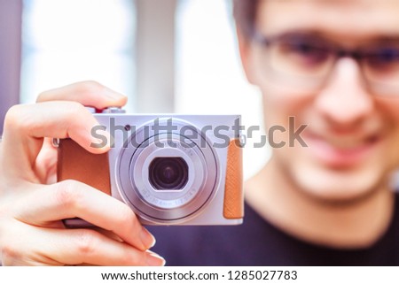 Young man with vintage camera smiles and takes a photo