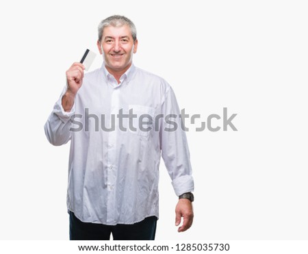 Handsome senior man holding credit card over isolated background with a happy face standing and smiling with a confident smile showing teeth