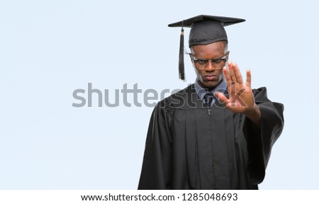 Young graduated african american man over isolated background doing stop sing with palm of the hand. Warning expression with negative and serious gesture on the face.