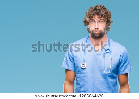 Handsome hispanic surgeon doctor man over isolated background puffing cheeks with funny face. Mouth inflated with air, crazy expression.