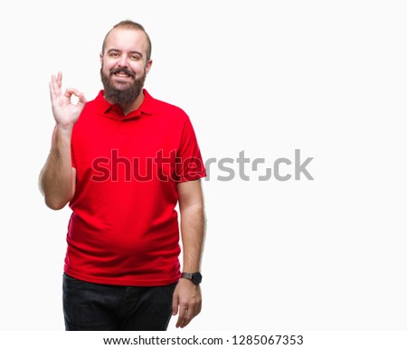 Young caucasian hipster man wearing red shirt over isolated background smiling positive doing ok sign with hand and fingers. Successful expression.
