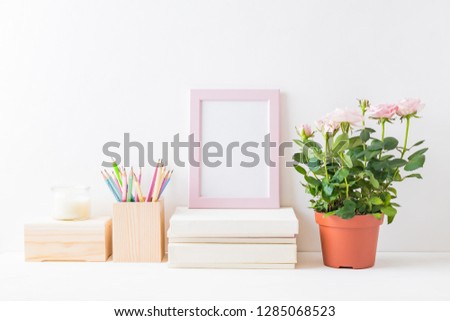 Home interior with decor elements. Pink frame, pink roses in a pot, interior decoration