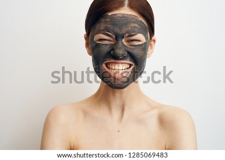 woman in a cosmetic mask of clay on a light background