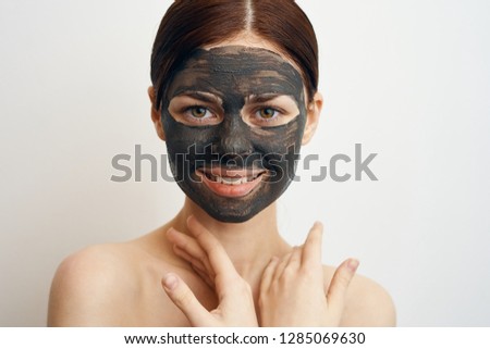 woman smiling in a cosmetic mask of clay on a light background