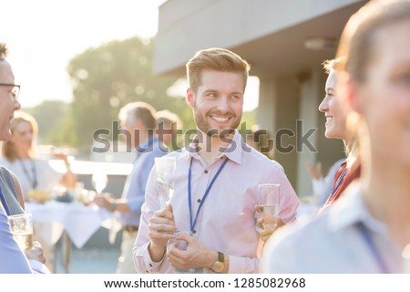 A group of attractive business colleagues enjoying a glass of champagne outside on a roof terrace in a restaurant or a bar. This could be a party, a convention, conference or a wedding event.