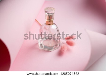 Bottle of perfume with flowers on color background. with pink paper. minimalistic