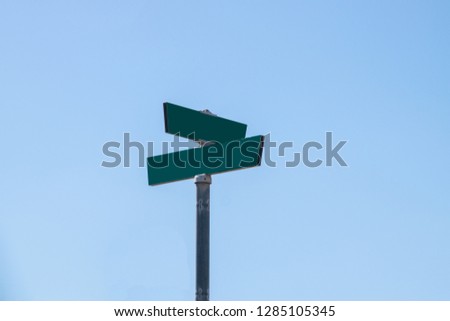 Blank green street signs on metal post with blue sky background