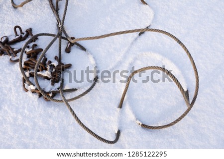 Steel wire rope cable and rusty chain in snow