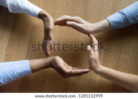 Above close up view four human hands businesswomen and businessman making a circle on wooden background, teammates join palms in shape of circle, protecting and showing care of their business concept