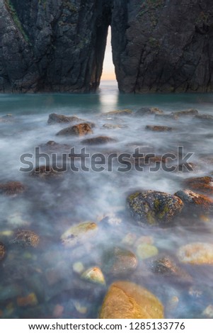 Usa, Oregon. Slow shutter speed of ocean spray over lichen covered rocks at arch, Harris Beach State Park