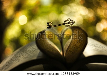 The book and the key to heart on the background of the green-orange bokeh Royalty-Free Stock Photo #1285133959