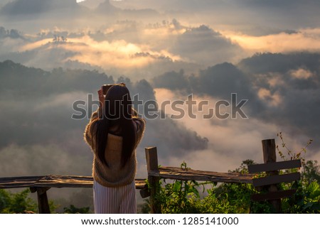 Young Asian woman take pictures in the sunrise view point of Ban Ja-Bo, Pang Ma Pha, Mae Hong Son, Thailand
