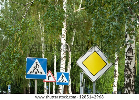 Road signs on a background of trees, main road, pedestrian crossing, traffic rules, driving