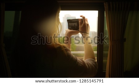 A woman takes photos of skyscrapers from a modern car.