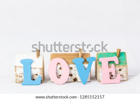 word love by colorful  letter plate  lean  wood house model on white background, home sweet home concept with copy space