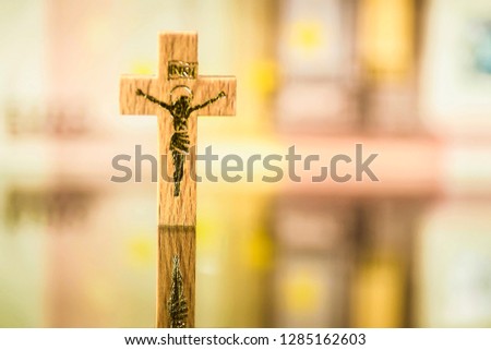 Wooden crucifix against a fuzzy euro banknote