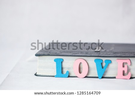 word love by colorful  letter plate  lean over bible or hand book on white background, home sweet home concept with copy space