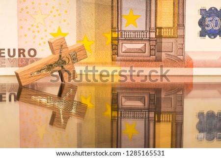 Wooden crucifix on the background of the euro banknote