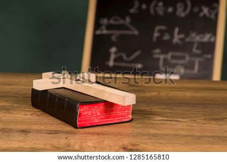 A crucifix on a book against the background of a written school board